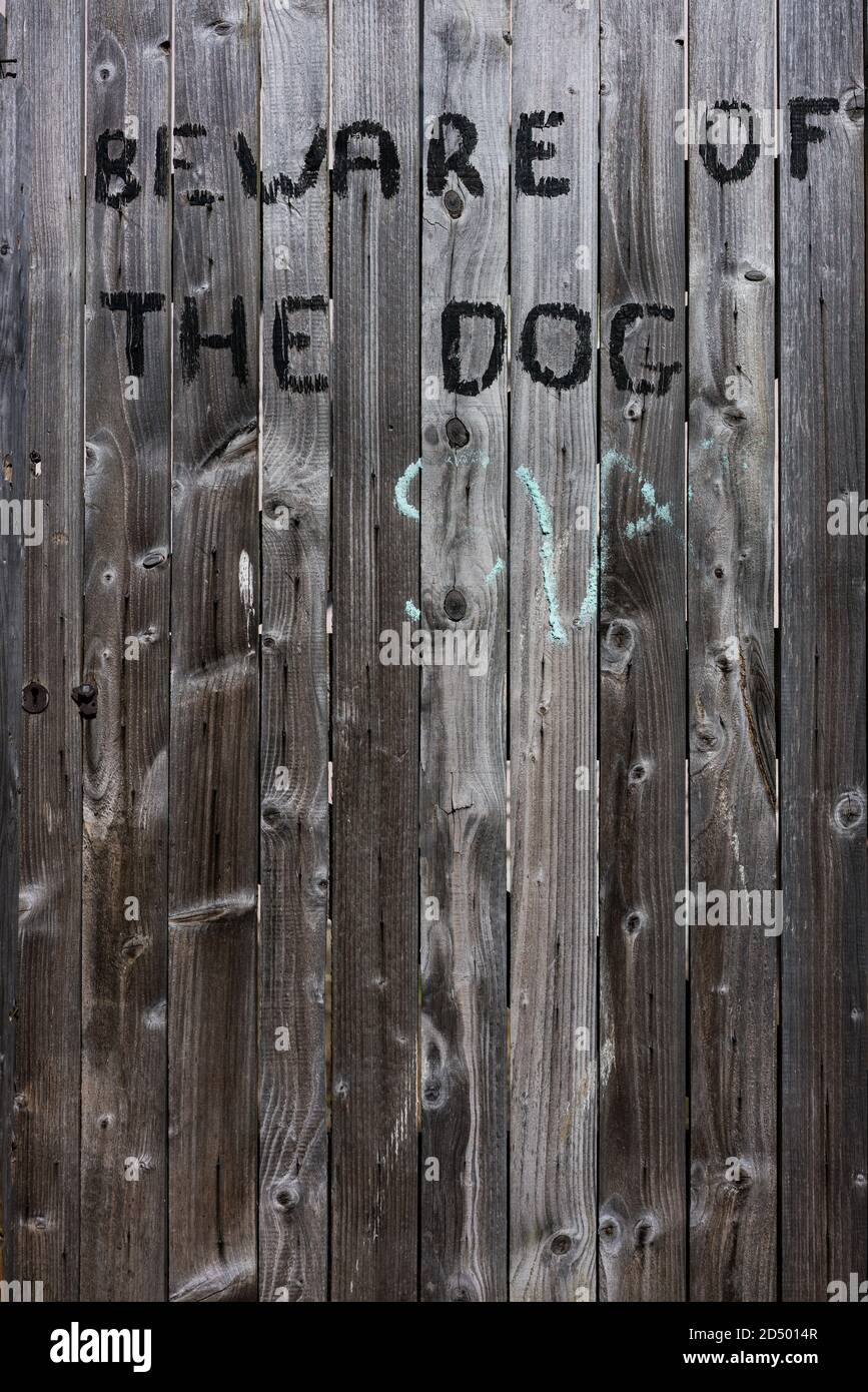 'Beware of the dog' roughly painted onto a rustic wooden gate Stock Photo