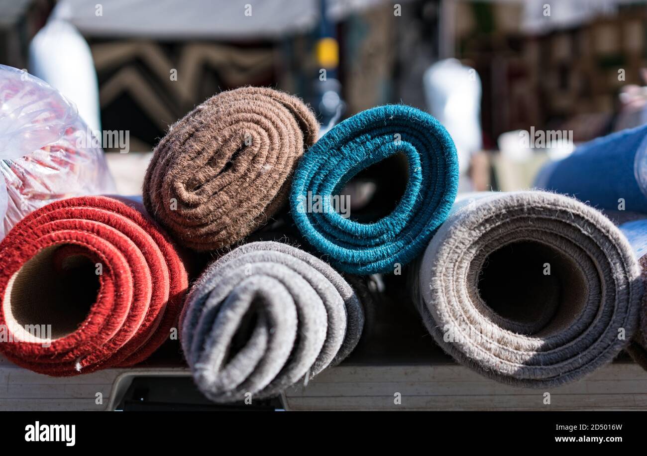 Close-up of the end of colourful, rolled-up rugs on an outside market stall in Colwyn Bay, Wales Stock Photo