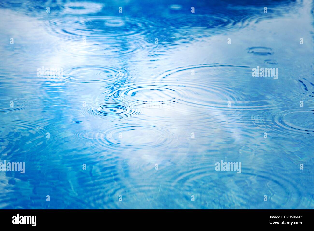 Raindrops on pool blue water surface. blue water texture as background. Stains circles on the water from rain Stock Photo
