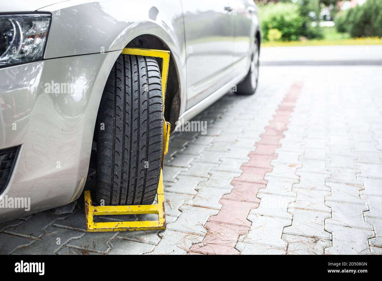 Yellow wheel clamp on an illegally parked car Stock Photo