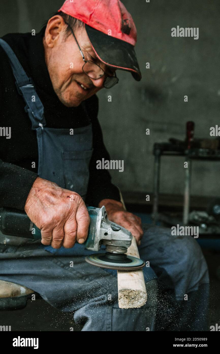 Old man working with a grinder Stock Photo