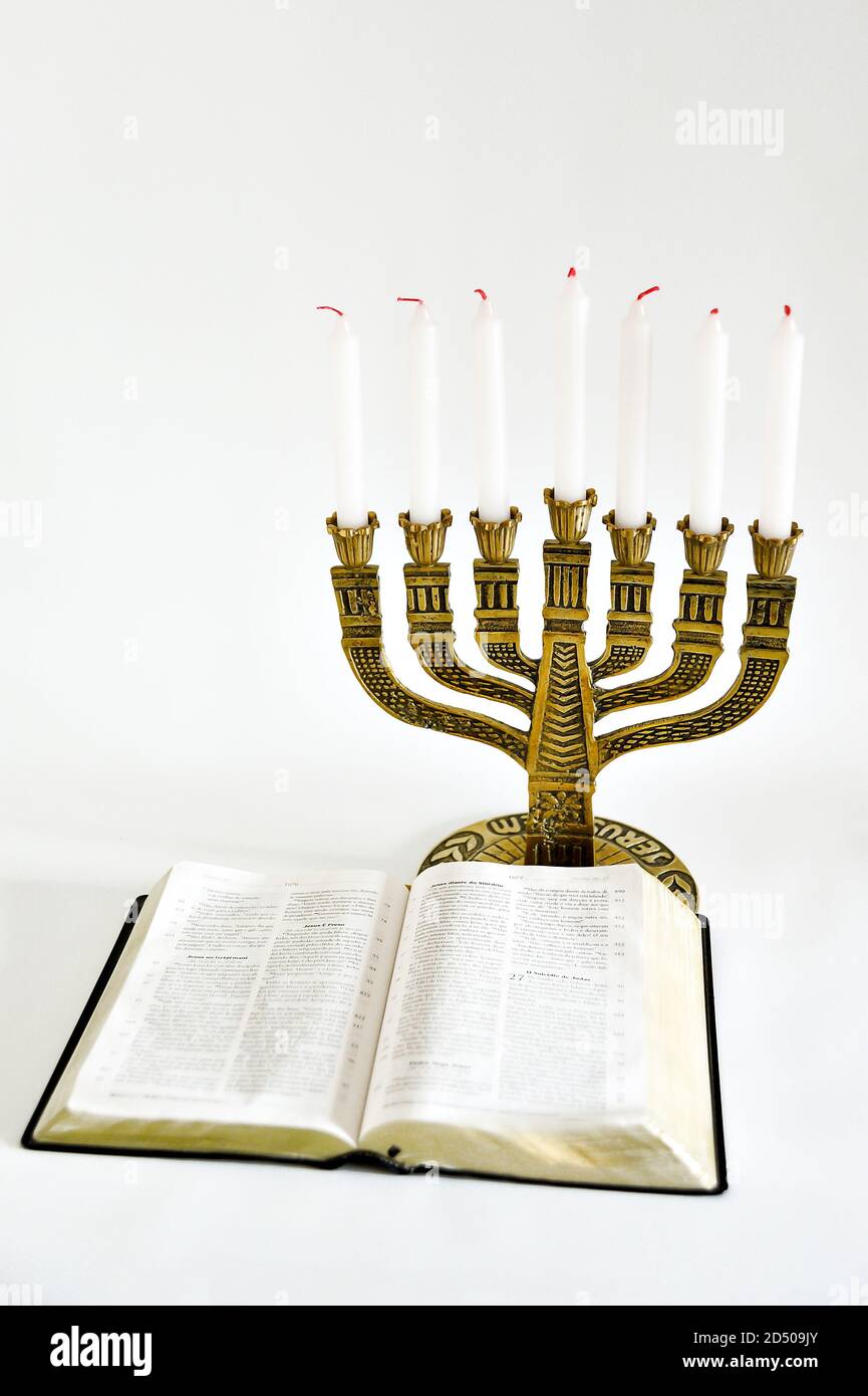 Menorah and open bible with 7 unlit candles isolated on white