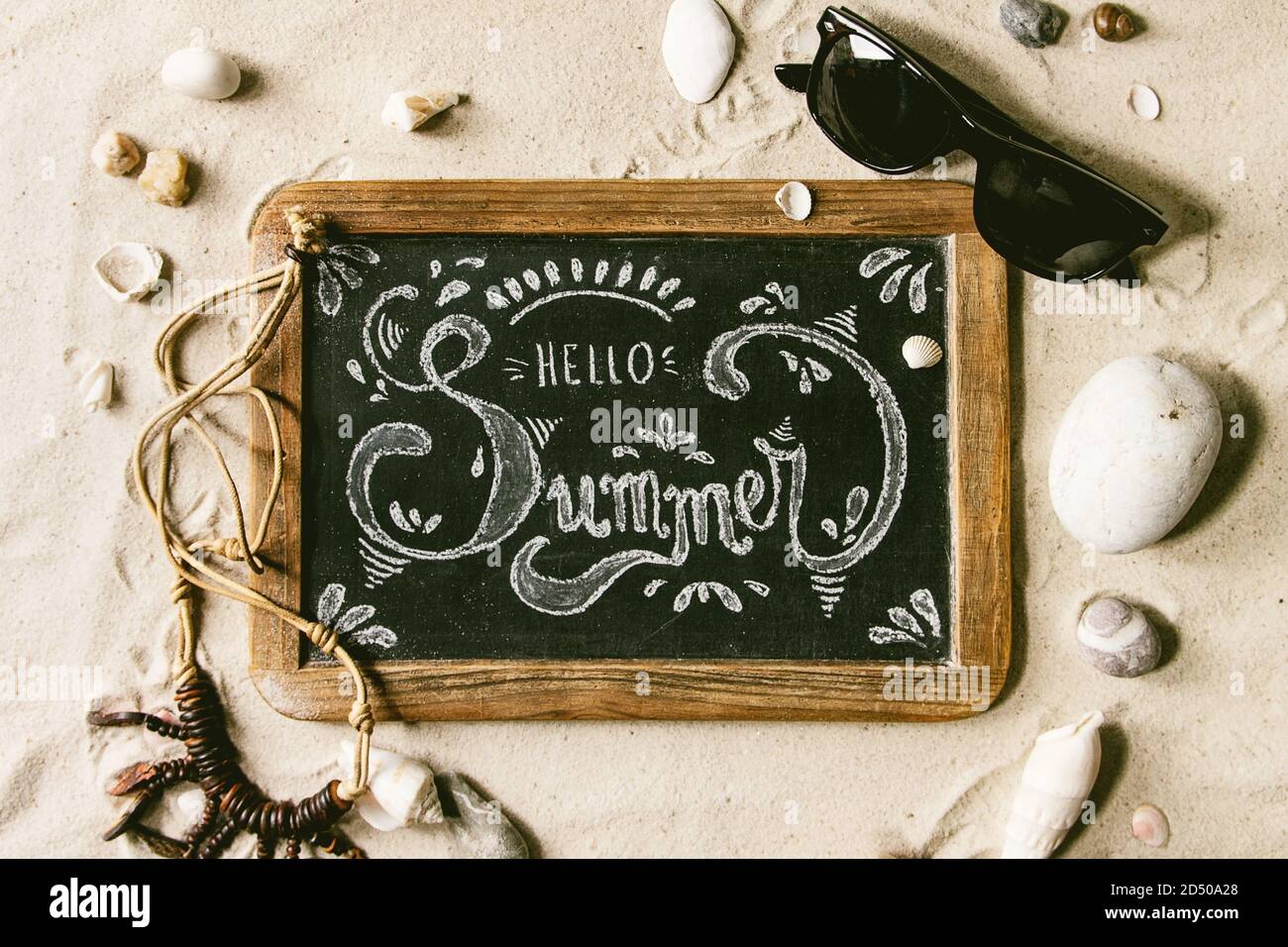 Summer theme. Chalk lettering Hello summer on vintage chalkboard, shells,  sea stones, sunglasses, wooden beads on white sand as background. Flat lay  Stock Photo - Alamy