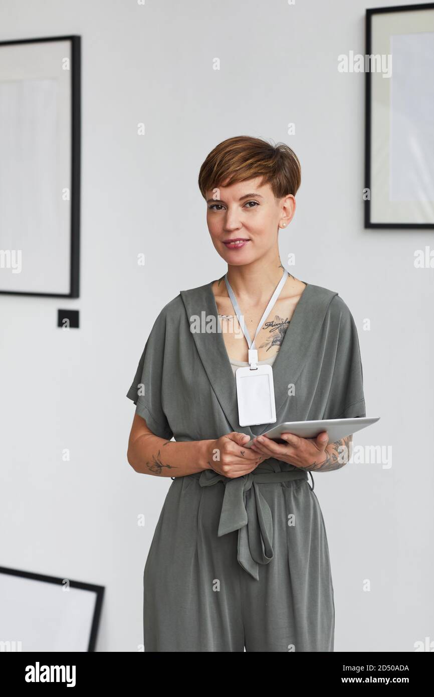 Vertical Portrait Of Female Art Gallery Manager Holding Digital Tablet And Looking At Camera 