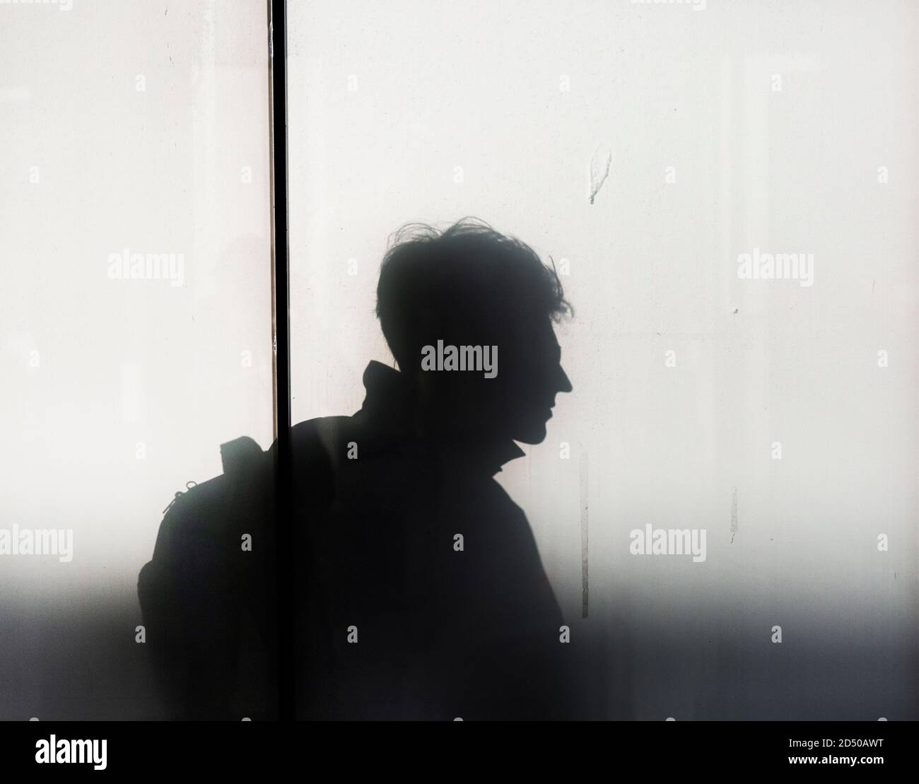 Silhouetted profile of a man through frosted glass Stock Photo
