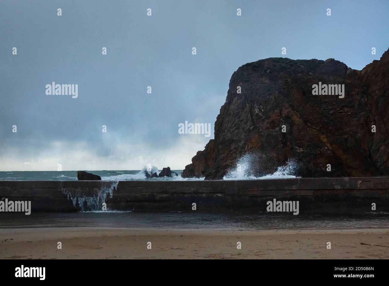 Waves crashing over wall sea defence Stock Photo