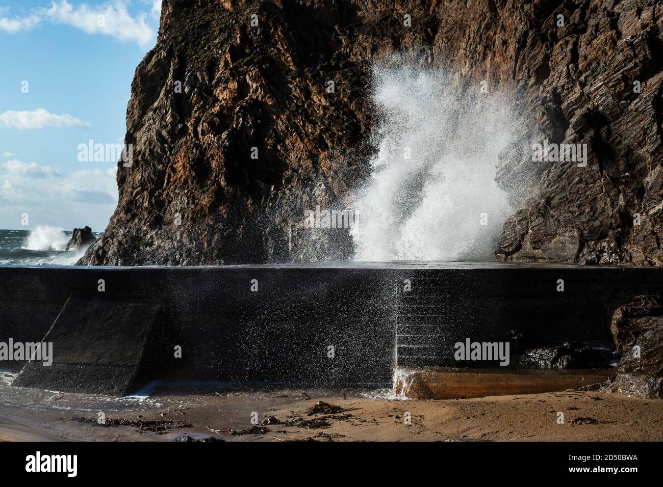 Waves crashing over wall sea defence Stock Photo