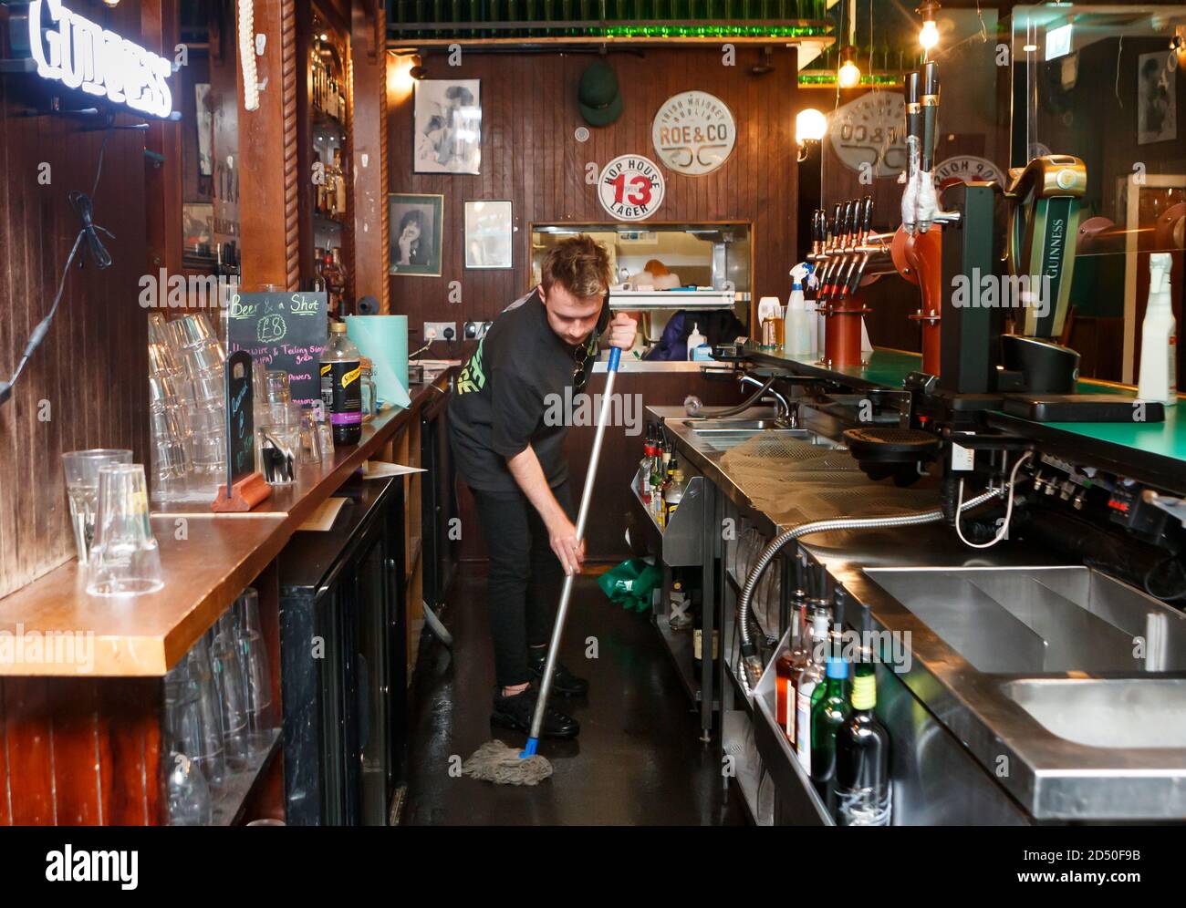 A staff member in The Corner Boy pub mopping the floor and closing up for the evening, in Manchester. The Government is expected to announce new measures later today that could see pubs and bars forced to close to combat the spread of the virus in northern England and other areas suffering a surge in Covid-19 cases. Stock Photo