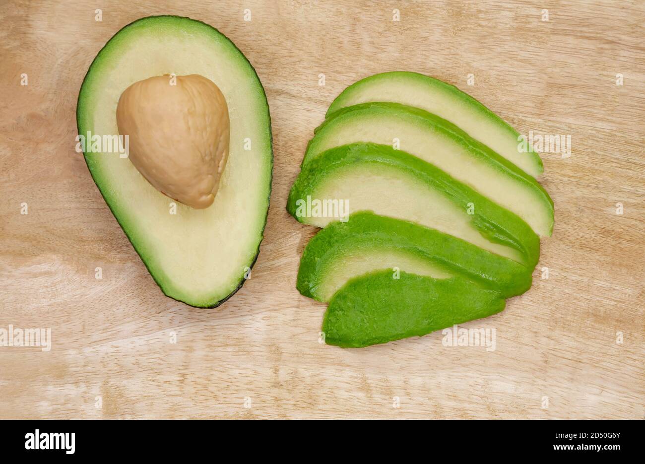 Sliced avocado with knife on wooden cutting board Stock Photo - Alamy