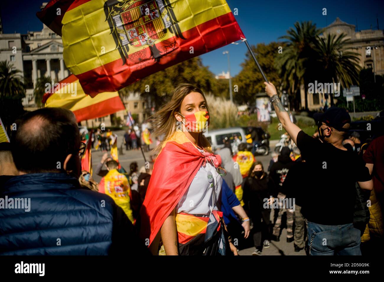Barcelona, Spain. 12th Oct, 2020. A woman wearing a face mask to prevent the spread of coronavirus walks past a Spanish Francoist flag as unionist gather at the bottom of Columbus statue in Barcelona during Spain's National Day. Credit:  Jordi Boixareu/Alamy Live News Stock Photo