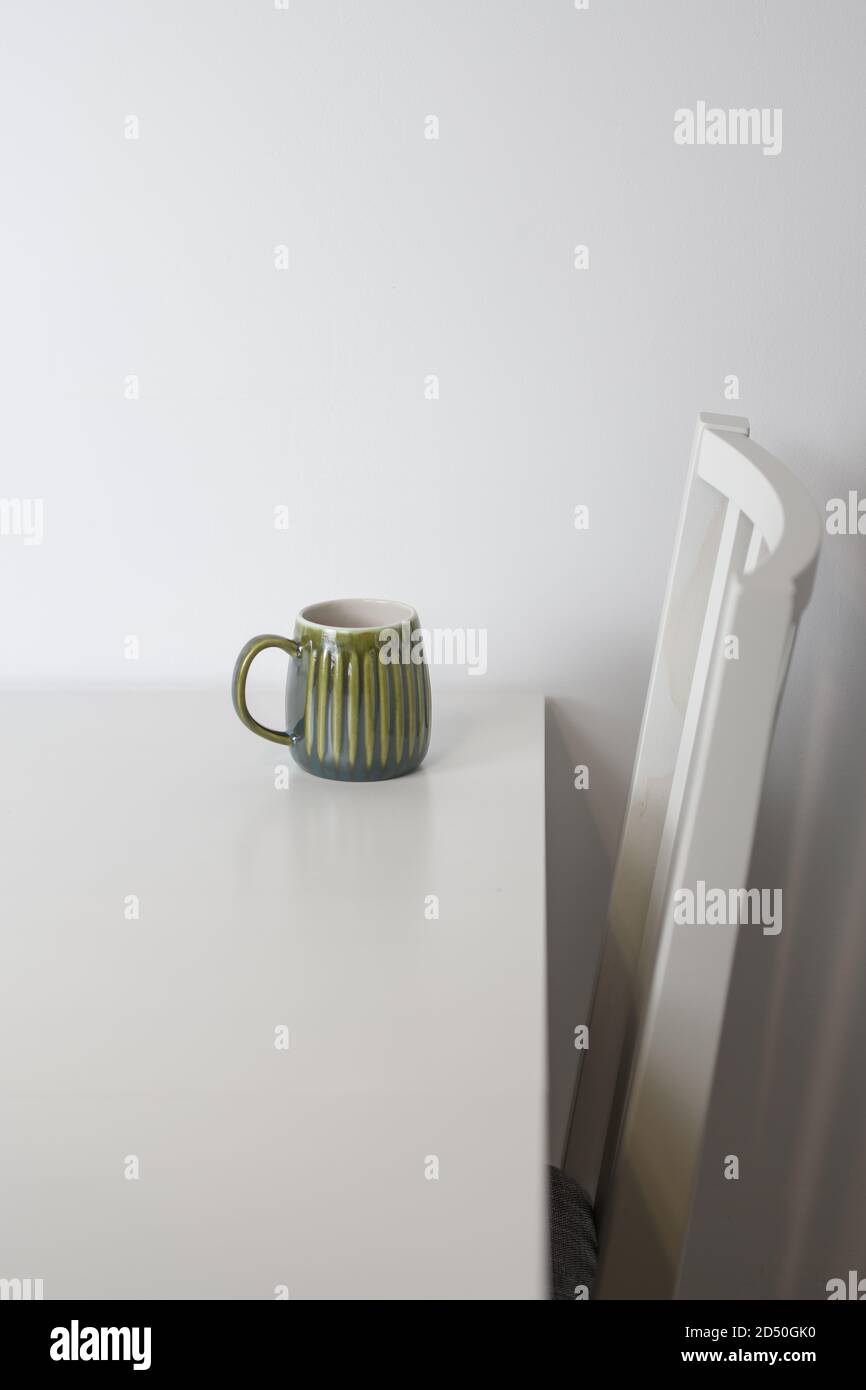 Green mug on a white table and a white chair Stock Photo