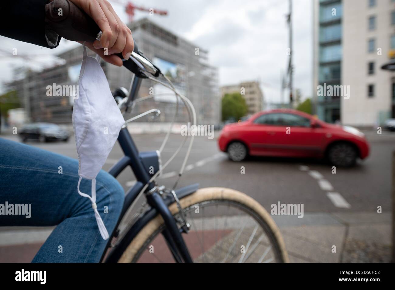 12 October 2020, Baden-Wuerttemberg, Stuttgart: A woman is standing on the City Ring with her bicycle, on which a mouth and nose guard is attached. On Saturday, 10 October 2020, the warning value of 50 new infections per 100,000 inhabitants in seven days was exceeded in Stuttgart. As of Wednesday, 14 October, masks will be mandatory in the city centre within the City Ring. Photo: Sebastian Gollnow/dpa Stock Photo