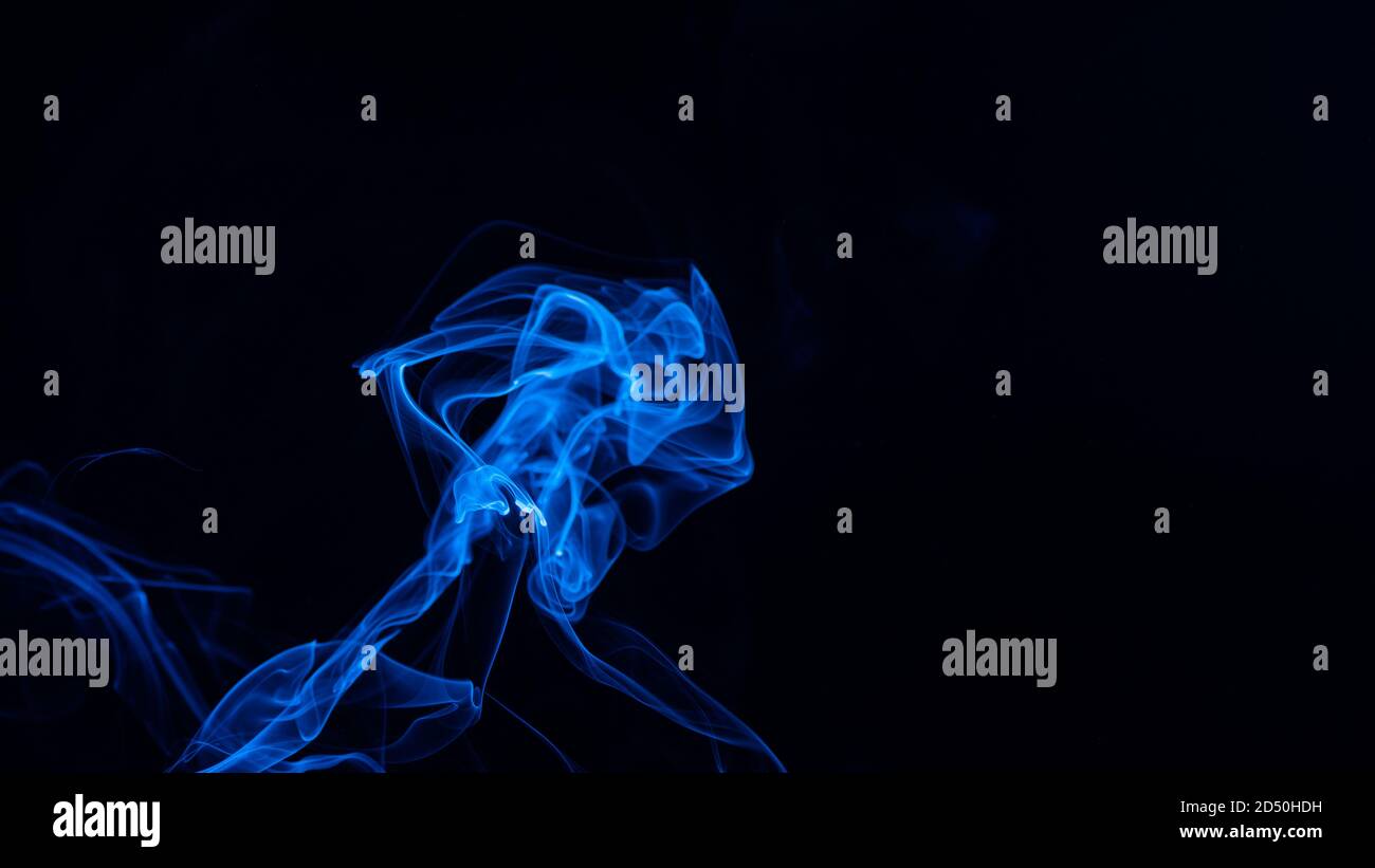 Conceptual image of blue color smoke isolated on dark black background ...