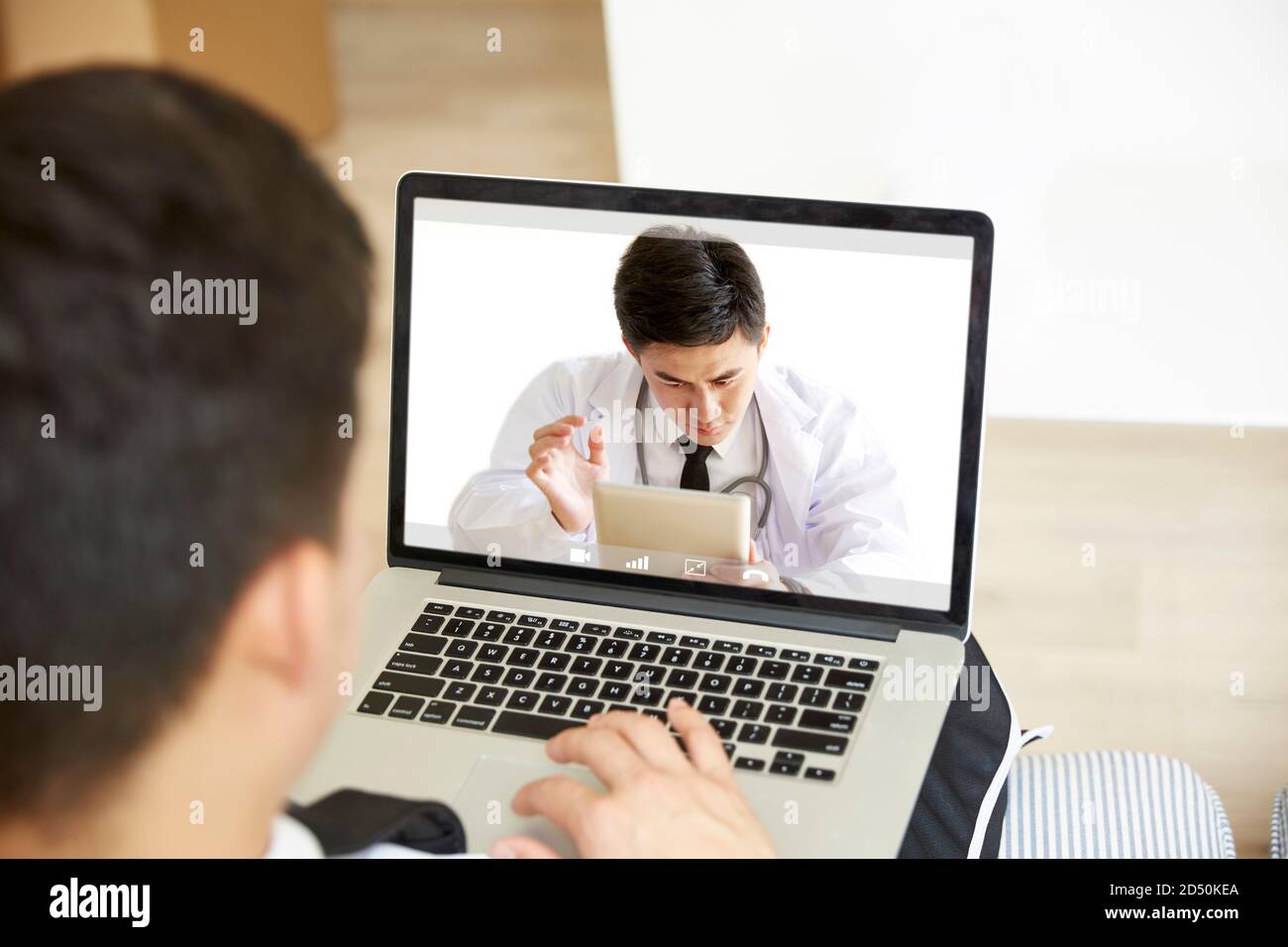 young asian man staying at home consulting primary care doctor online via video chat using laptop computer Stock Photo