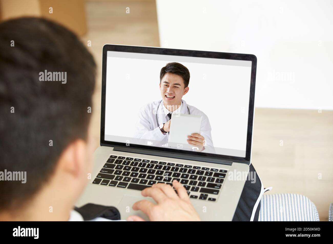 young asian man staying at home consulting primary care doctor online via video chat using laptop computer Stock Photo