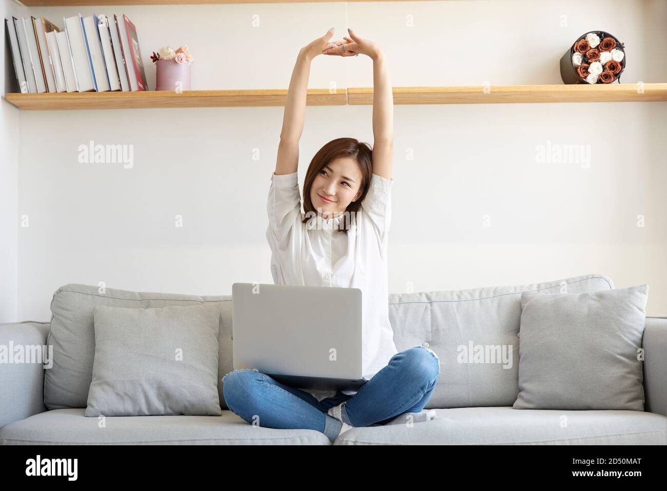 young asian business woman working from home sitting on couch stretching arms happy and smiling Stock Photo