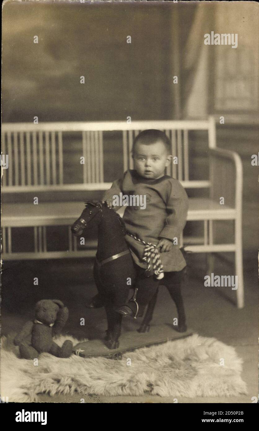Kleinkind in Feldgrau auf einem Spielzeugpferd, Teddybär | usage worldwide Stock Photo
