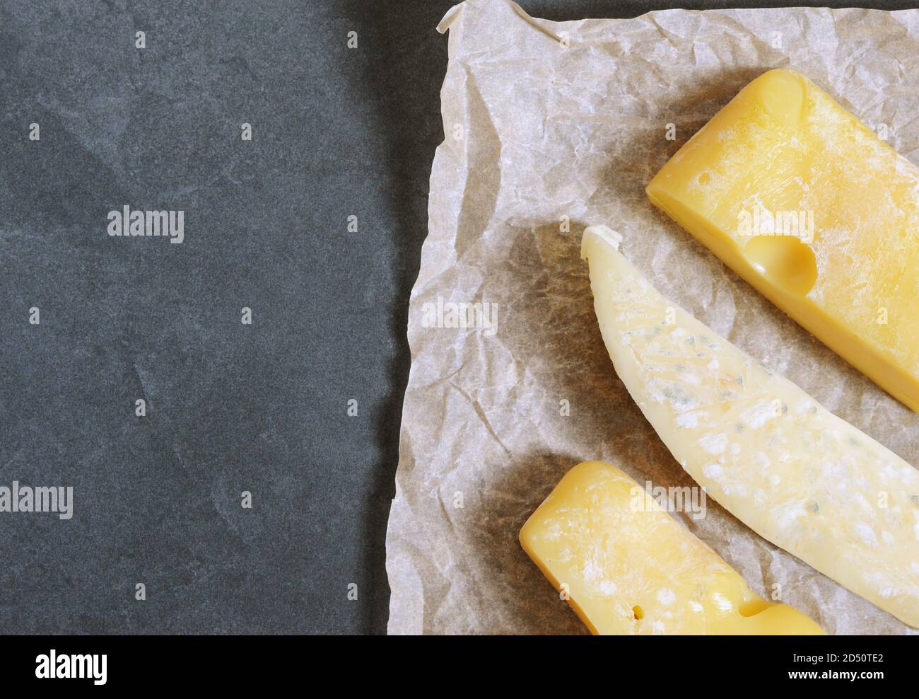 Mold on cheese. Hard cheese with white and black mold on it on the paper.  Moldy fungus on food.  Fluffy spores mold . Stock Photo