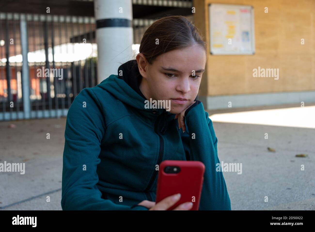 young woman sitting outside ,looking at smartphone  video appel looking bored  ,wearing sportswear . Stock Photo