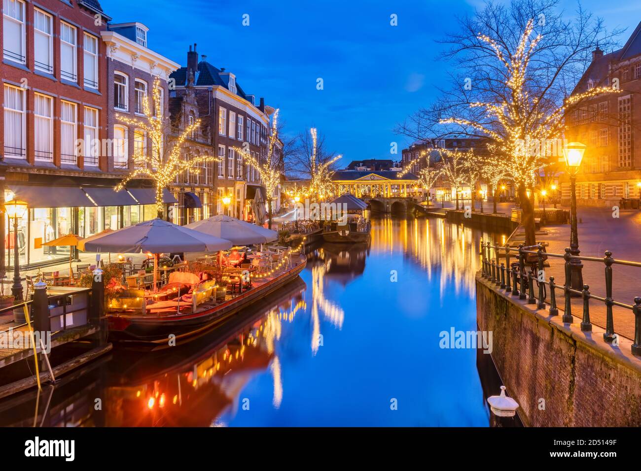 Ancient view of the Dutch Oude Rijn canal with bridge, historic buildings and christmas lights in the city center of Leiden, The Netherlands Stock Photo