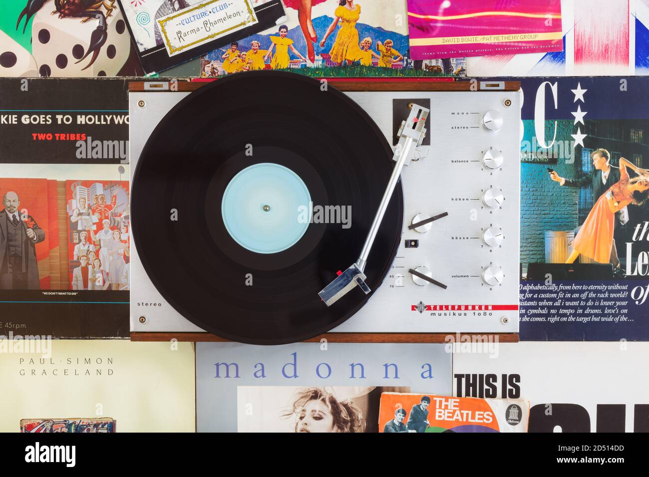 Dieren, The Netherlands - October 7, 2020: Vintage record player with spinning record on a background of old pop music records and singles in Dieren, Stock Photo