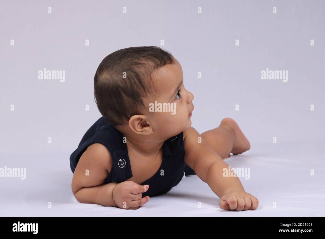 Happy Indian baby lying over white background. Stock Photo