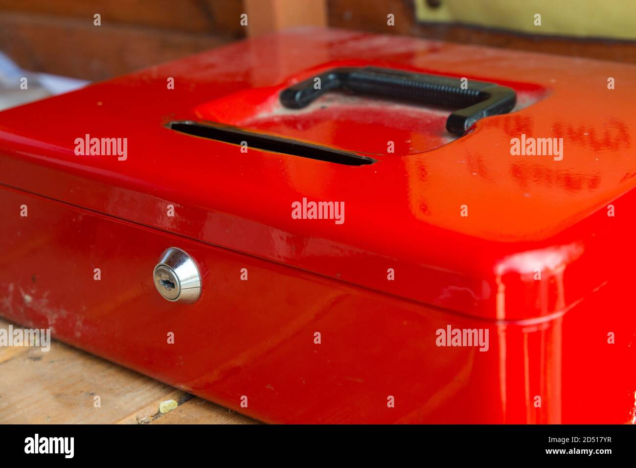 close up of shiny red money box with coin slot and lock and black