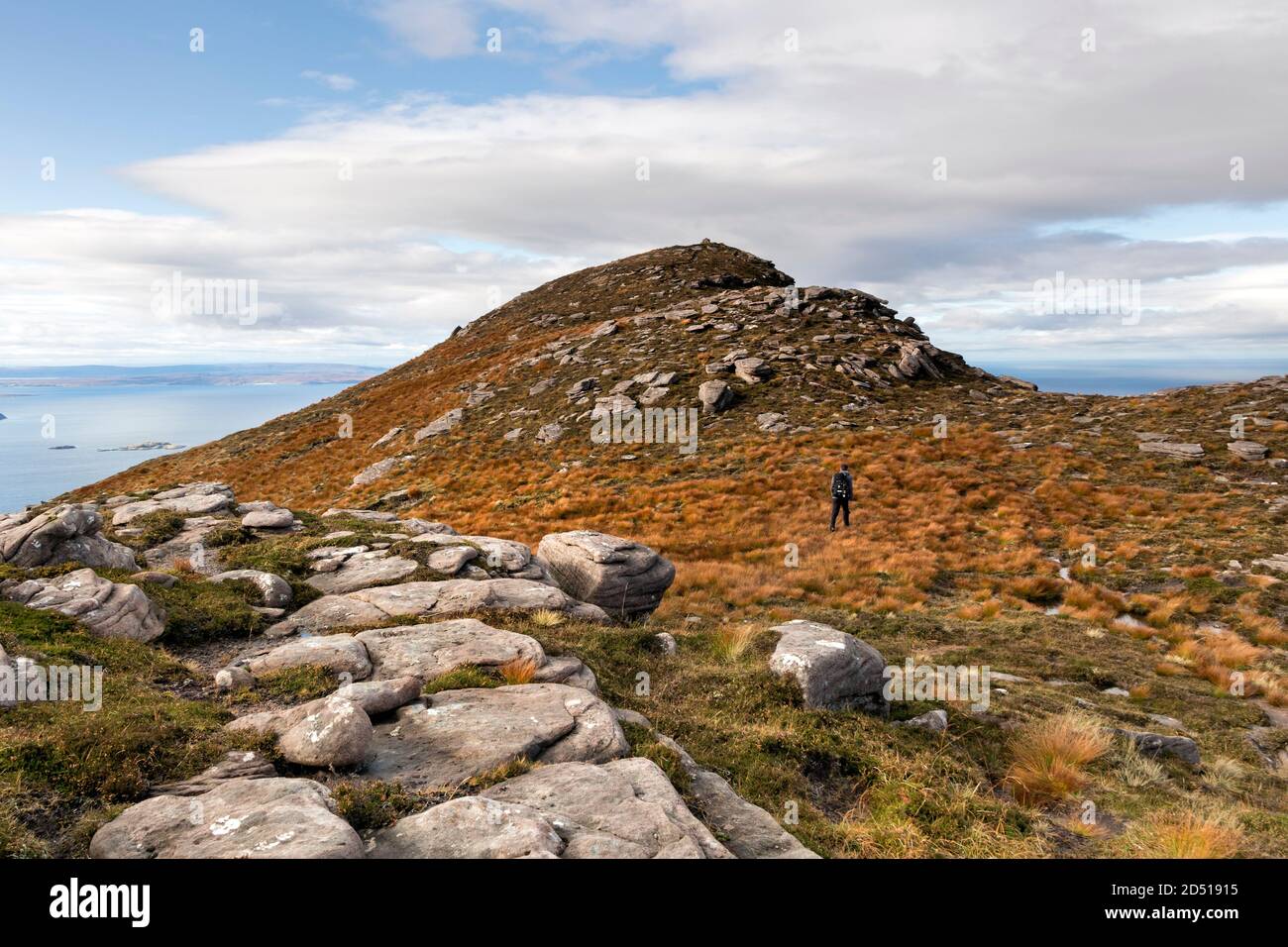 Walker Approaching the Summit of Cairn Conmheall,  Coigach Peninsula, Wester Ross, Northwest Highlands of Scotland, UK Stock Photo