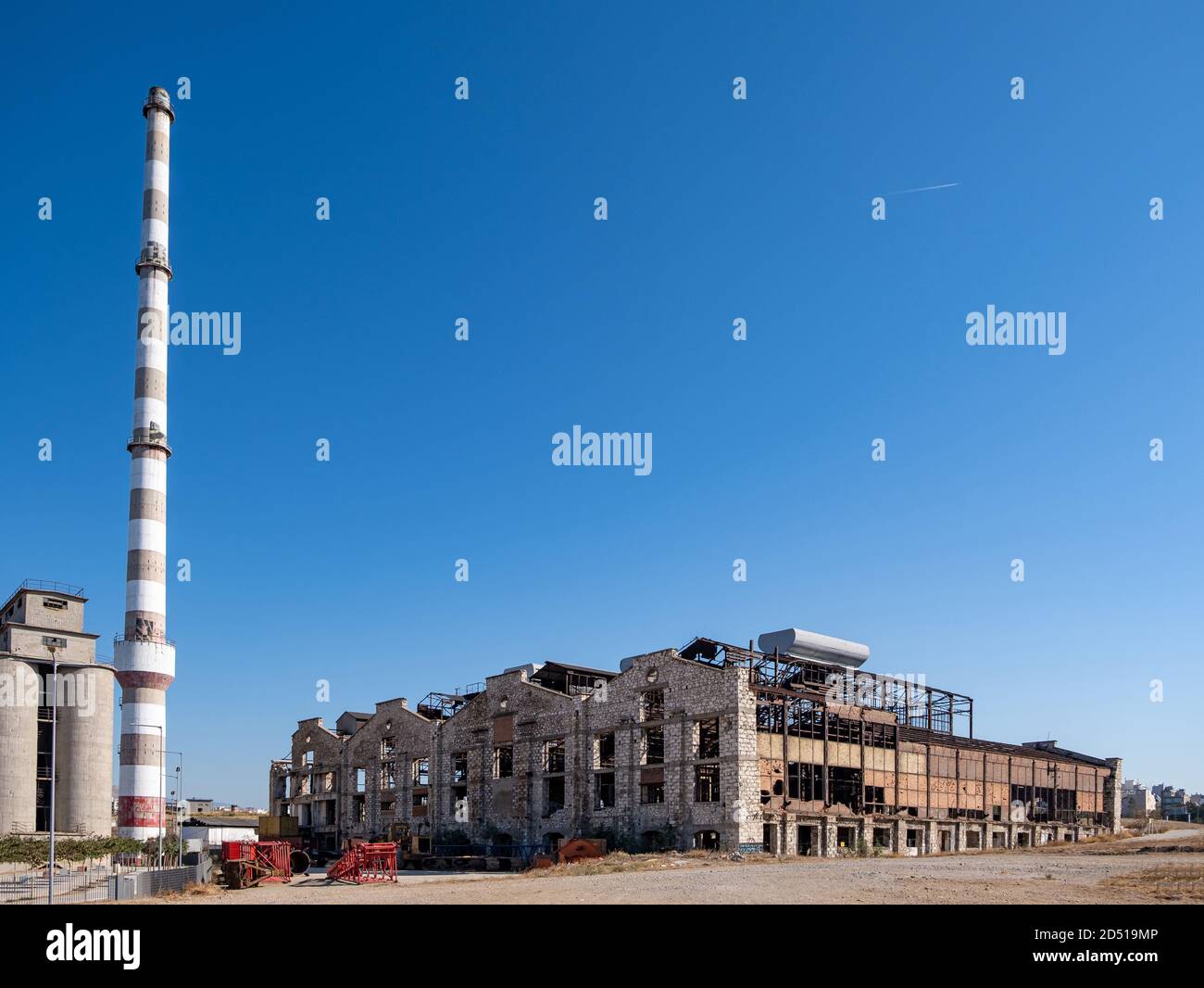 Old abandoned factory industrial plant. Fertilizer factory building and chimney ruins in Drapetsona Piraeus Greece, blue sky, sunny day. Stock Photo