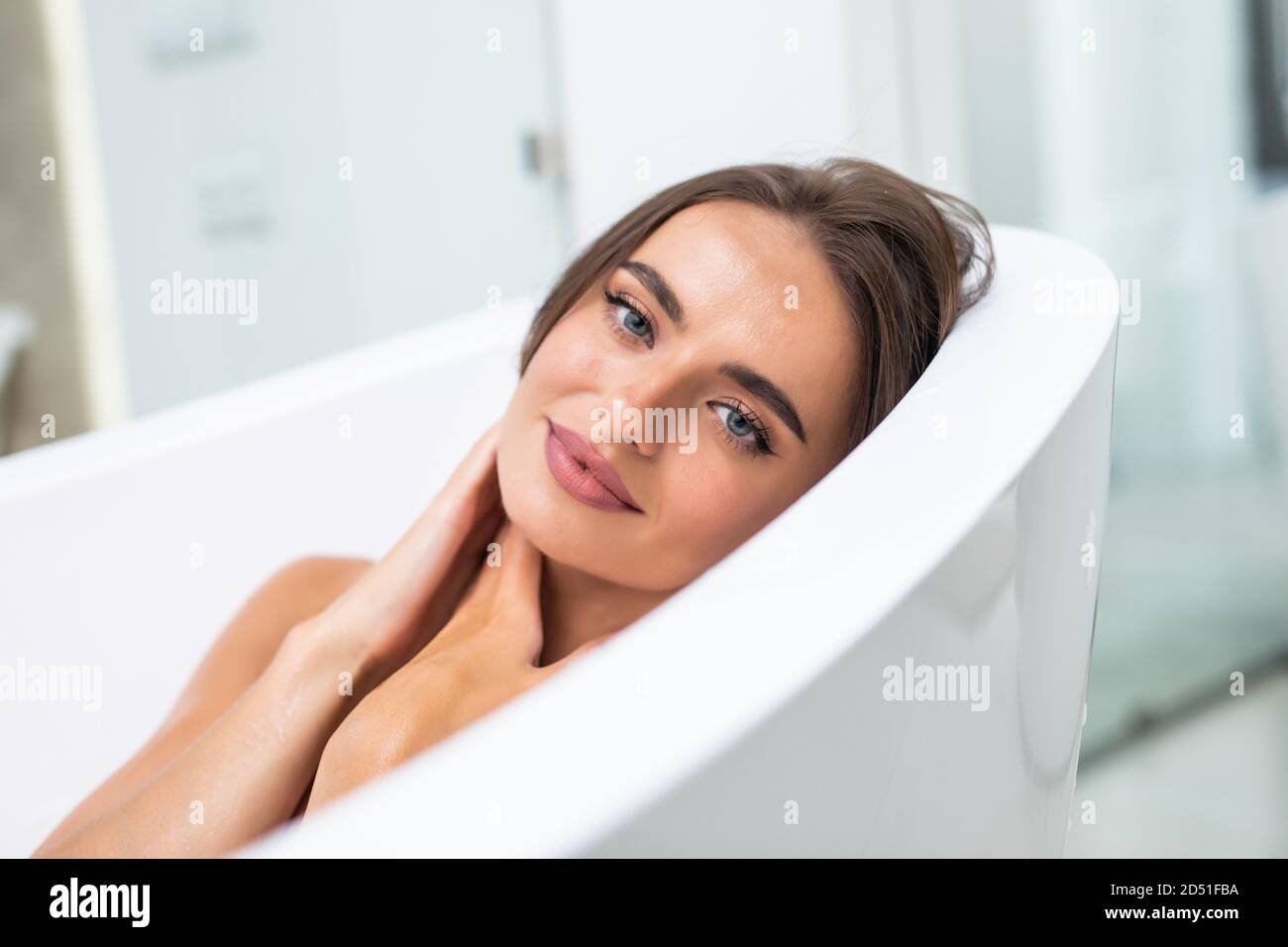 Young woman lying in bathtub in bathroom. Female relaxing in bathtub