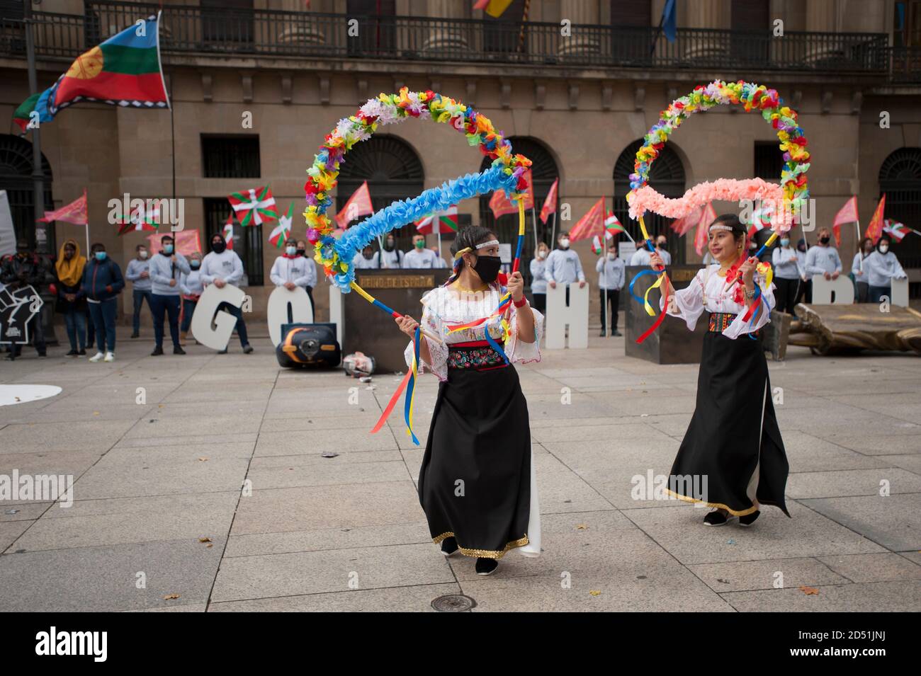 Pamplona, Spain. 12th Oct, 2020. Latin American women, (Cocanis of Oruro-Bolivia) are seen offering ancestral dances with masks, dances of the regions of Nicaragua and Bolivia, during the demonstration in Pamplona.Demonstrators organized by the radical sector of a political party, stage a demonstration performance where statues of the King of Spain, Philip VI and Christopher Columbus have been hanged, to criticize the imperial character of the Spanish Kingdom. Credit: SOPA Images Limited/Alamy Live News Stock Photo