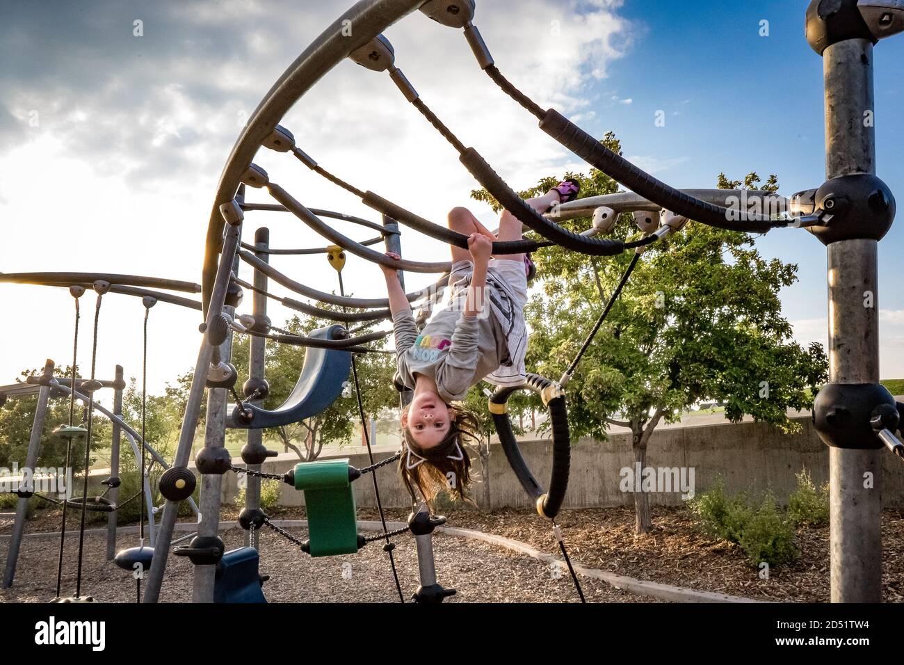young girl hangs upside down at playground Stock Photo - Alamy