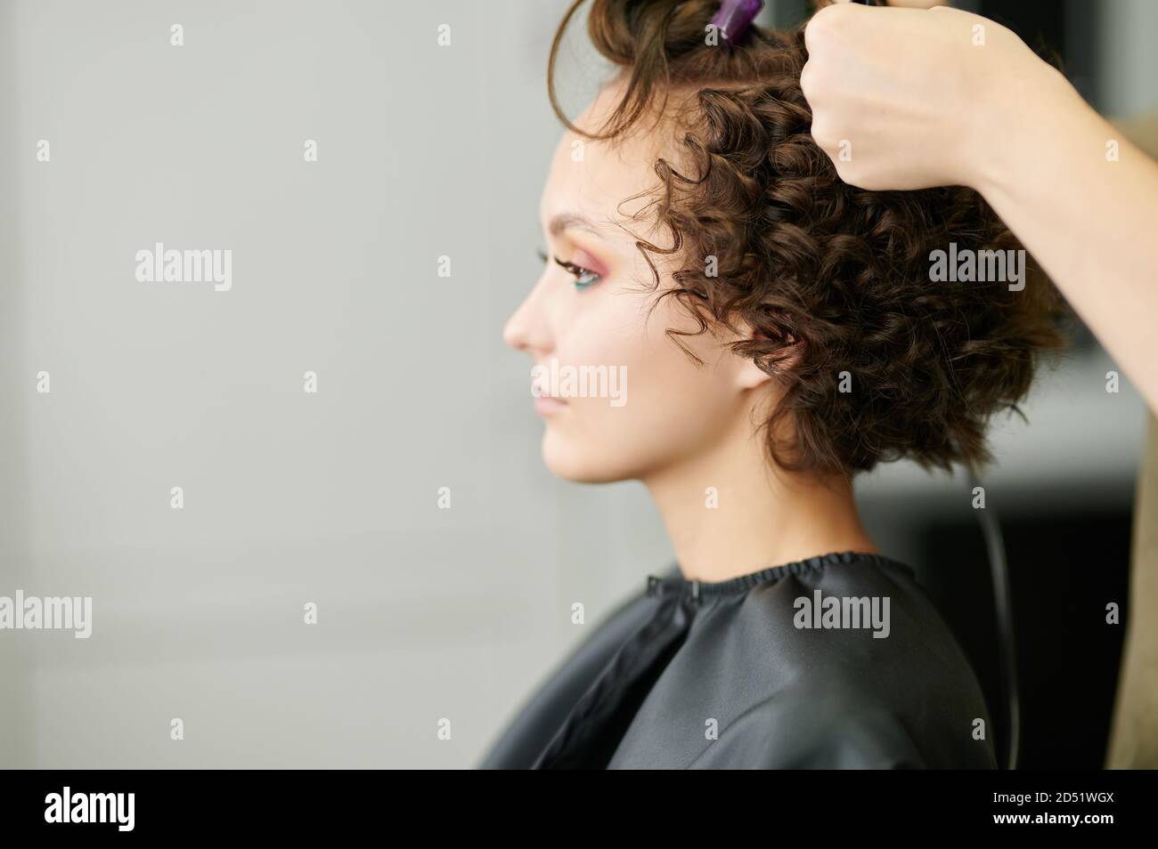 Making curly hair in professional salon side view Stock Photo