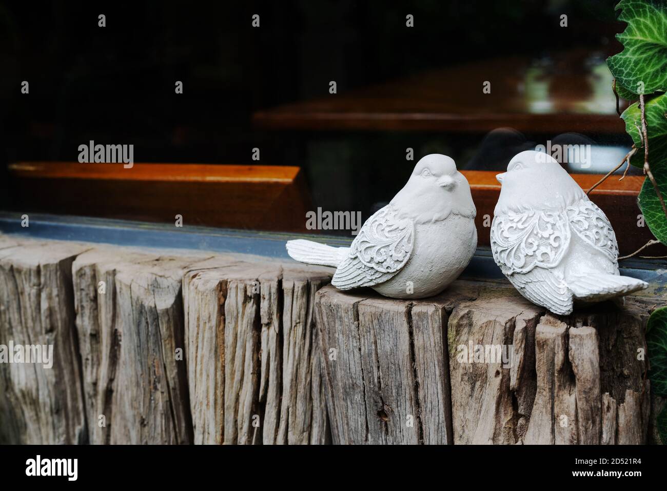 Couple birds, two white bird statues on the wooden near window Stock Photo