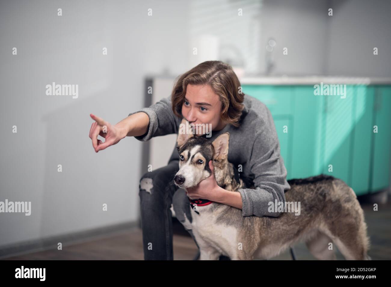 A woman playing with her dog. Goofing, petting and throwing a ball. A husky dog with its owner at home. Stock Photo