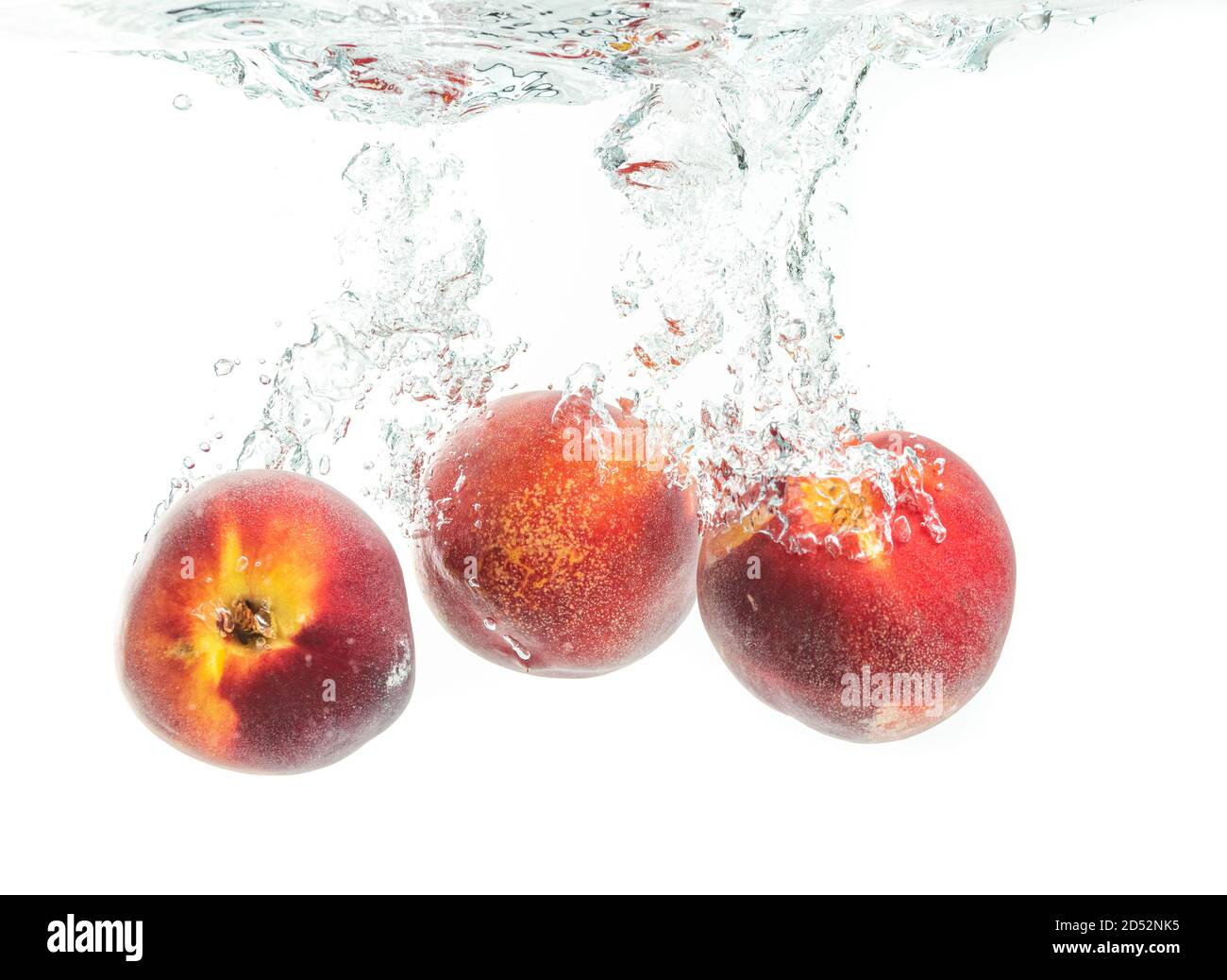 Three peaches falling into water with splash Stock Photo