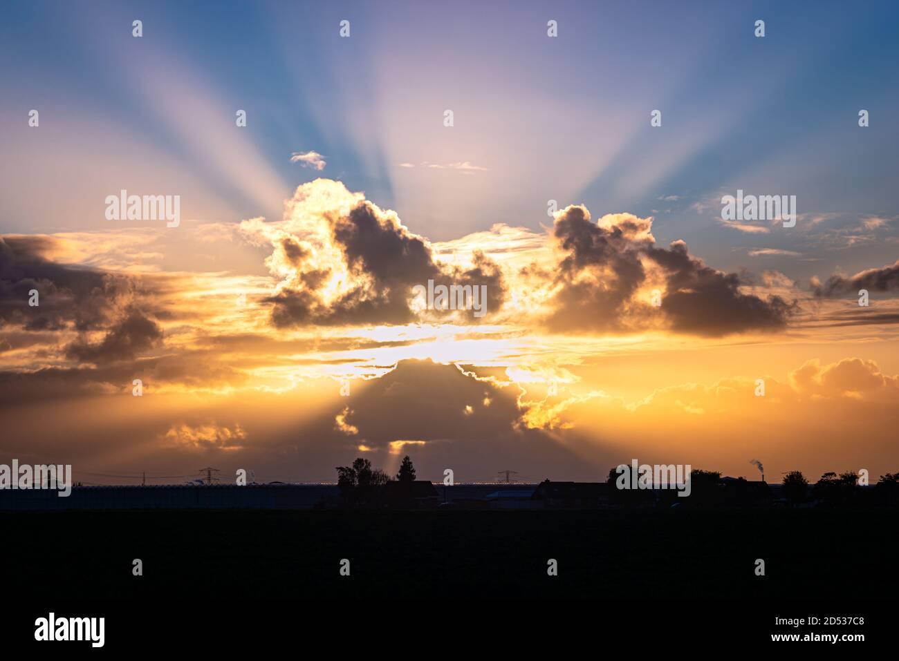 Sunbeams coming from behind colorful clouds Stock Photo