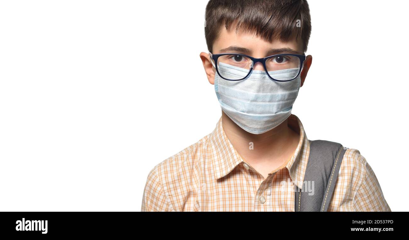 Close-up portrait of a schoolboy face with glasses and a protective mask looking at the camera. Stock Photo