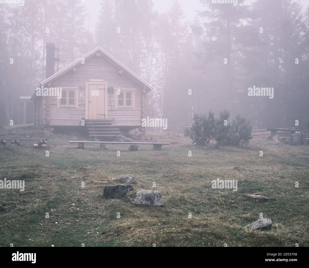 Log cabin in the forest with fog in the background Stock Photo