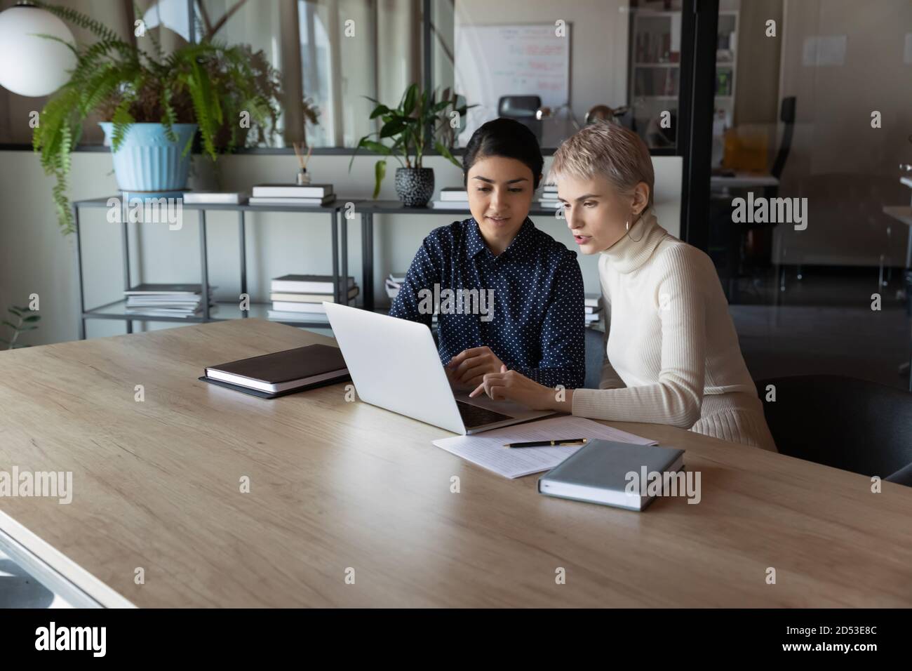 Concentrated multiethnic female colleagues work on laptop together ...
