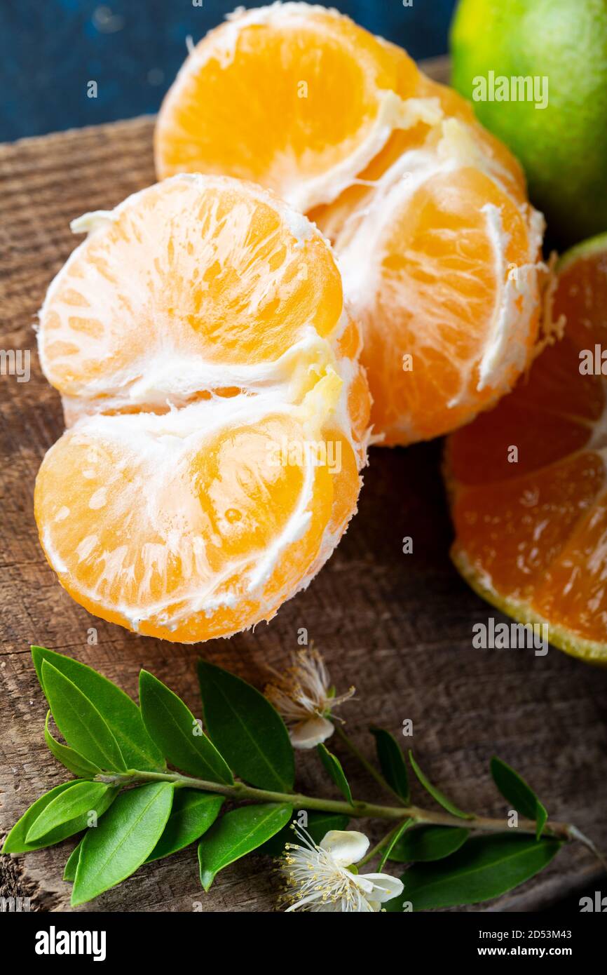 Ripe Mandarin fruit peeled open and place on old rustic look timber