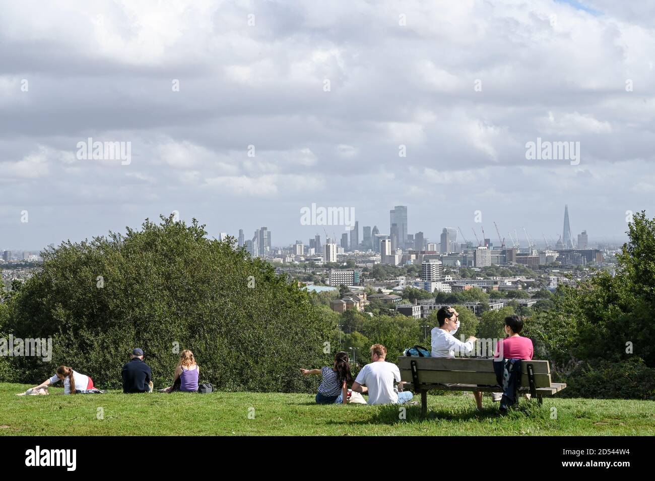 People chatting in small groups on Parliament Hill, London UK, with a view of London city sky line. Stock Photo