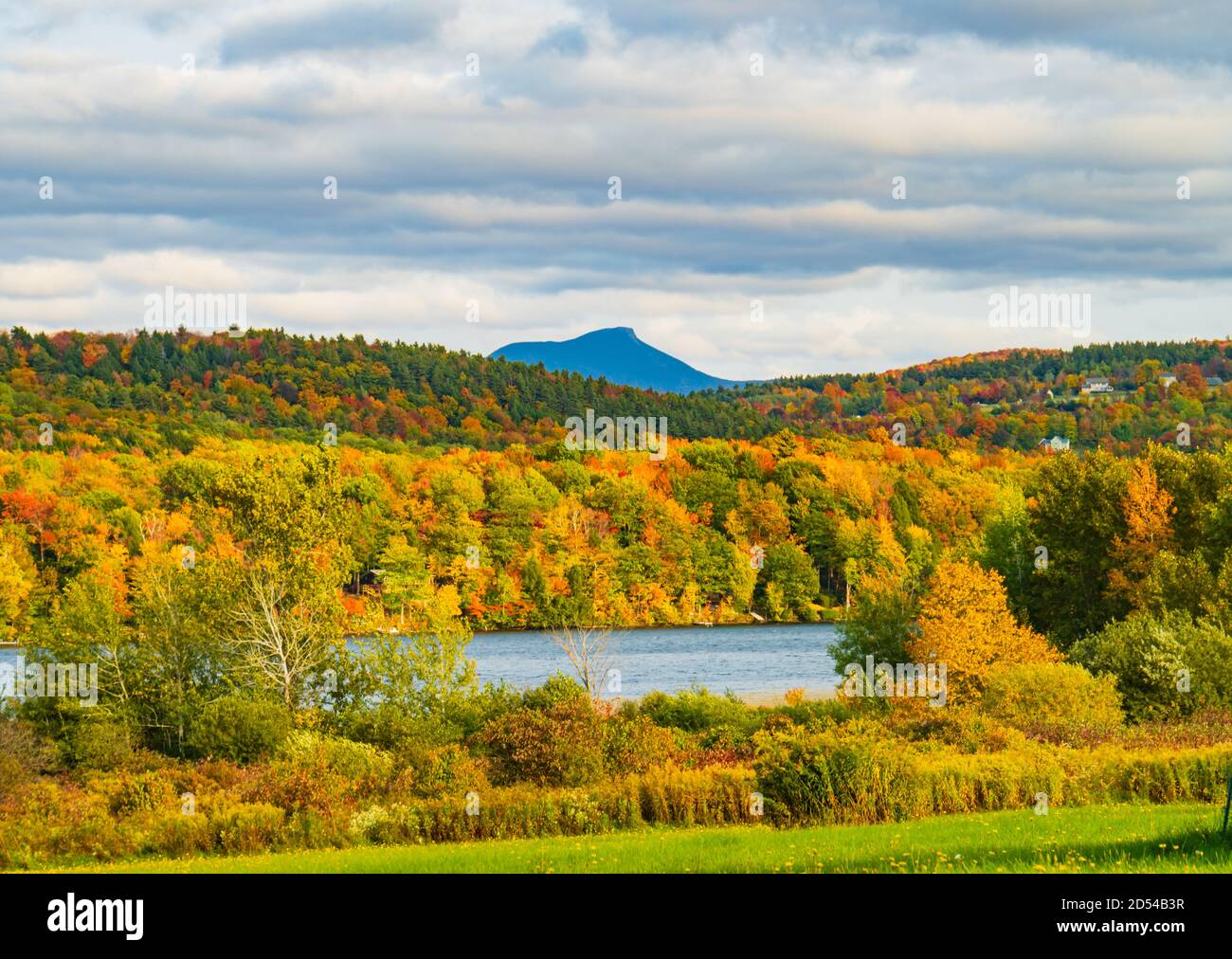 Lake Iroquois surrounded by forests in brilliant fall foliage colors with Camel's Hump Mountain in the distance Stock Photo