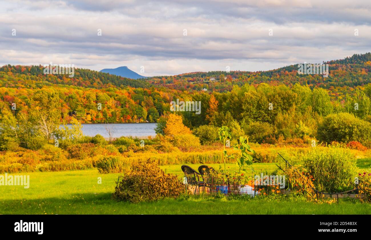 Lake Iroquois surrounded by forests in brilliant fall foliage colors with Camel's Hump Mountain in the distance Stock Photo