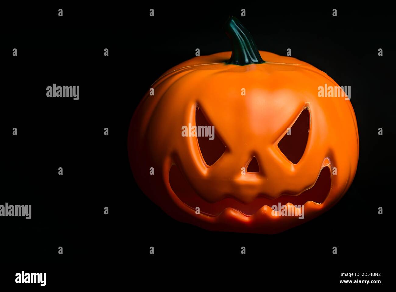 Ghostly isolated plastic Halloween orange pumpkin with scary face on ...