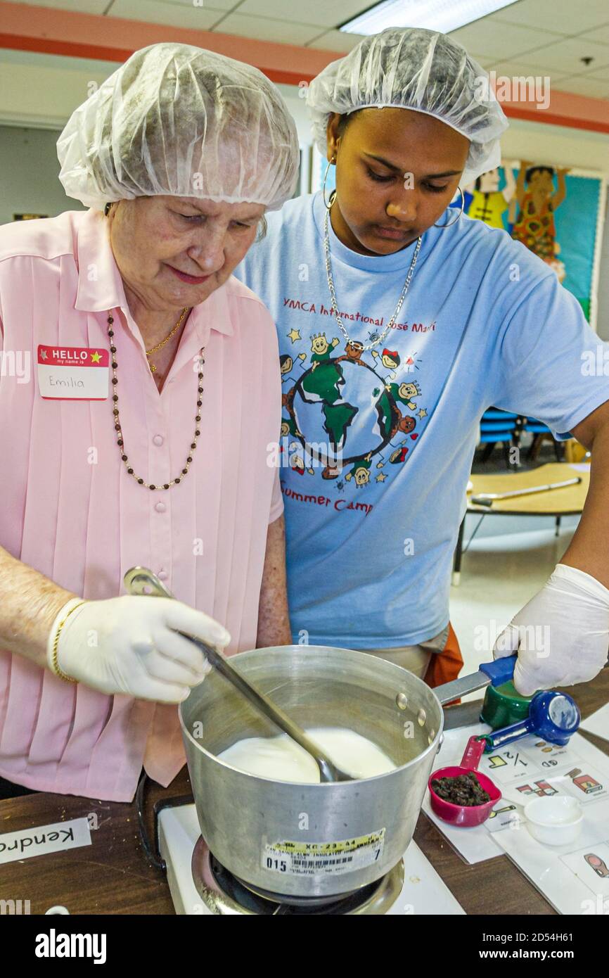 Miami Florida,Easter Seals Intergenerational Day,kitchen volunteer volunteers prepare preparing lunch food meals,Hispanic Black African woman female w Stock Photo