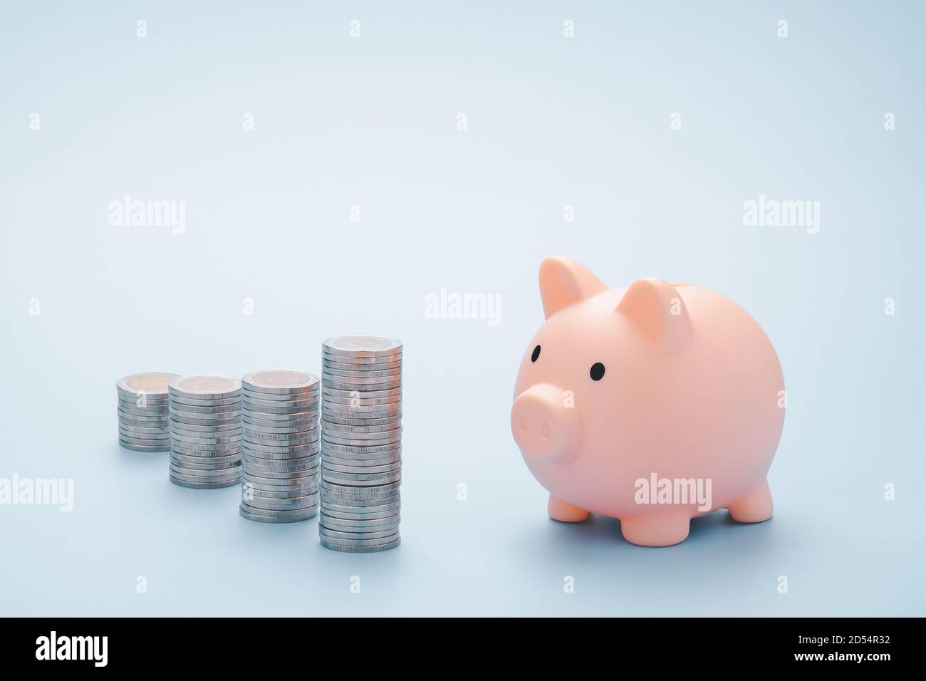 Pink piggy bank and coins isolated on Light blue background. Soft focus ...