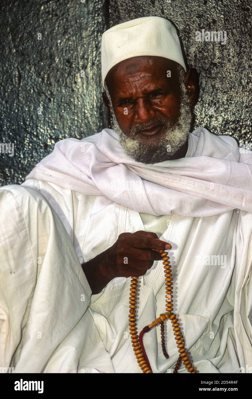 Bouake, Ivory Coast, Cote d'Ivoire.  Muslim Ivorian Man with Prayer Beads Relaxing while Waiting for Prayer Time Outside the Mosque. Stock Photo