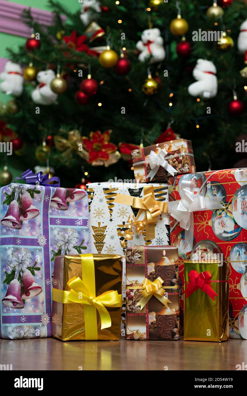 gift boxes wrapped with Christmas paper and colored bows, under a