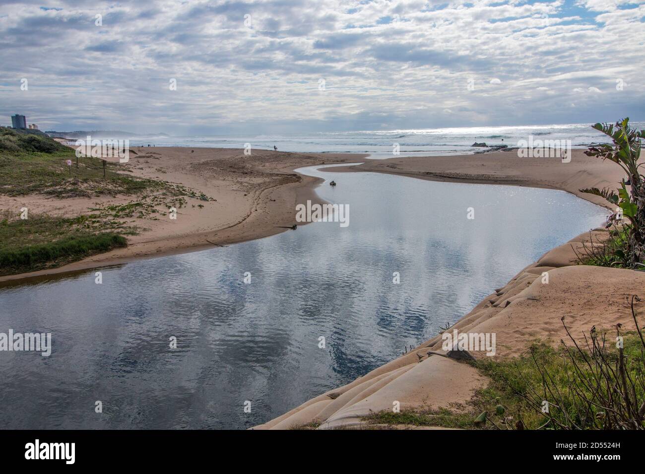 Clouds reflecting on river flowing into the sea Stock Photo - Alamy